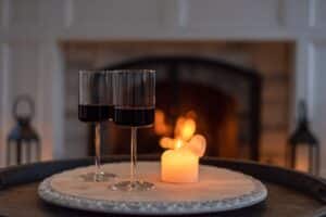 Two glasses of red wine at home by a cozy fireplace