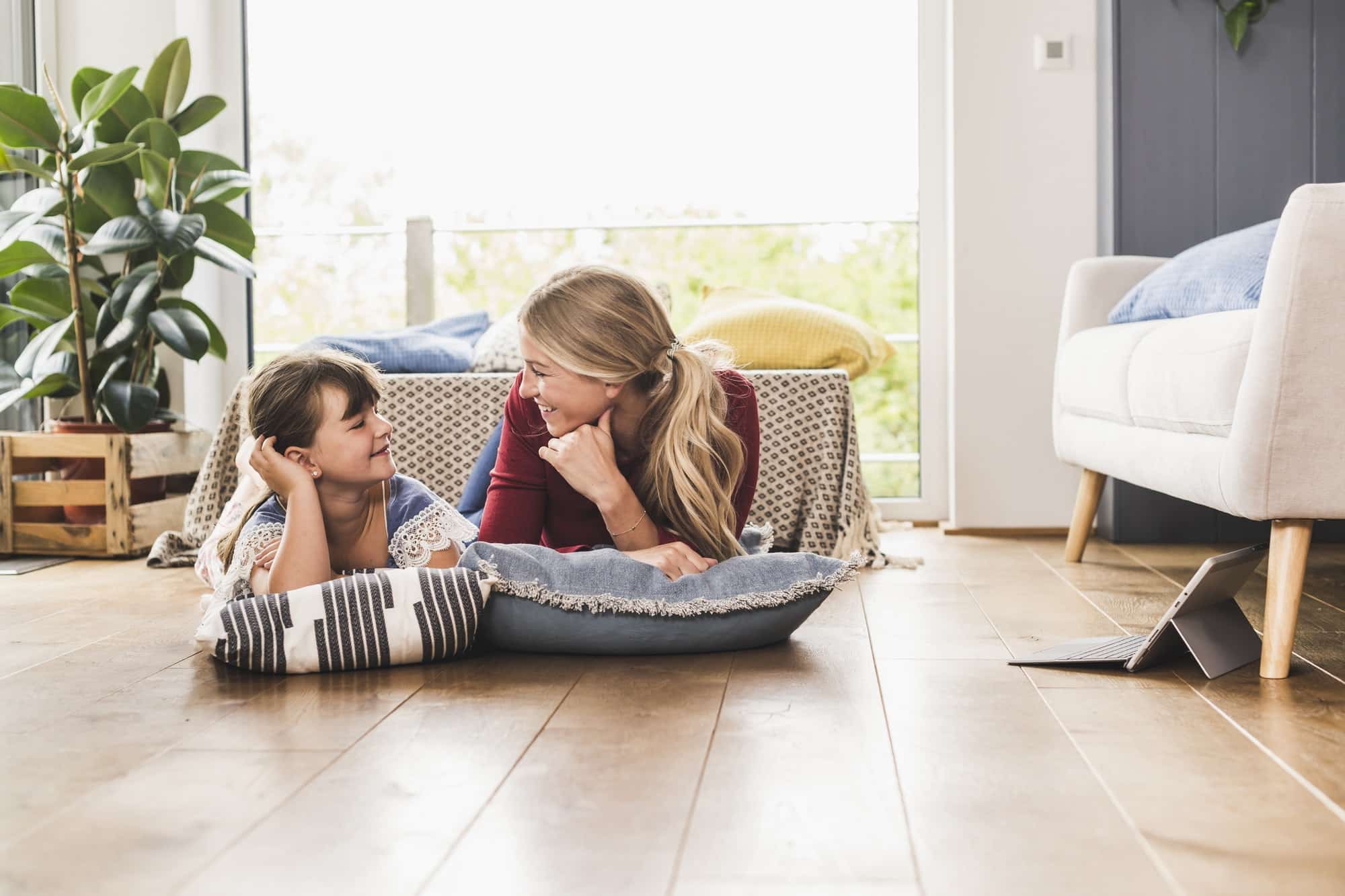 Mother and daughter lying on the floor at home looking at each other