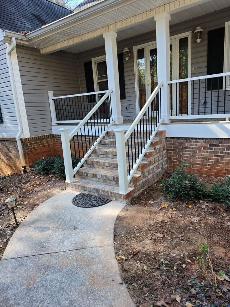 Custom front porch with white columns and black metal railings built by JCG in West Georgia
